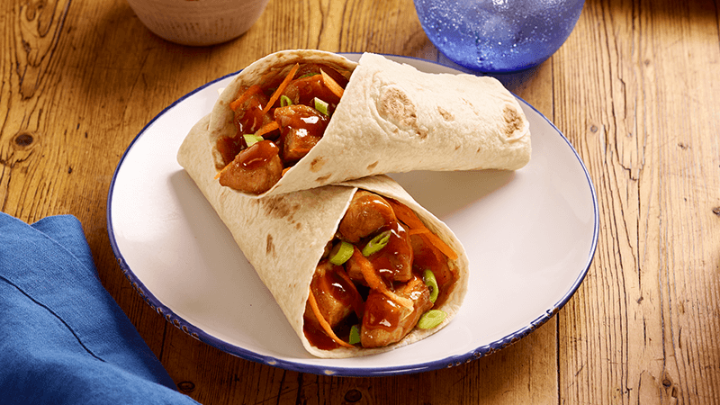 Teriyaki Fusion Fajitas served in a white plate surrounded by blue cloth on a wooden table